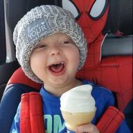 Happy child in a hat holding ice cream, with a Spider-Man car seat in the background.