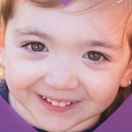 Smiling child with brown eyes, wearing a dark shirt.