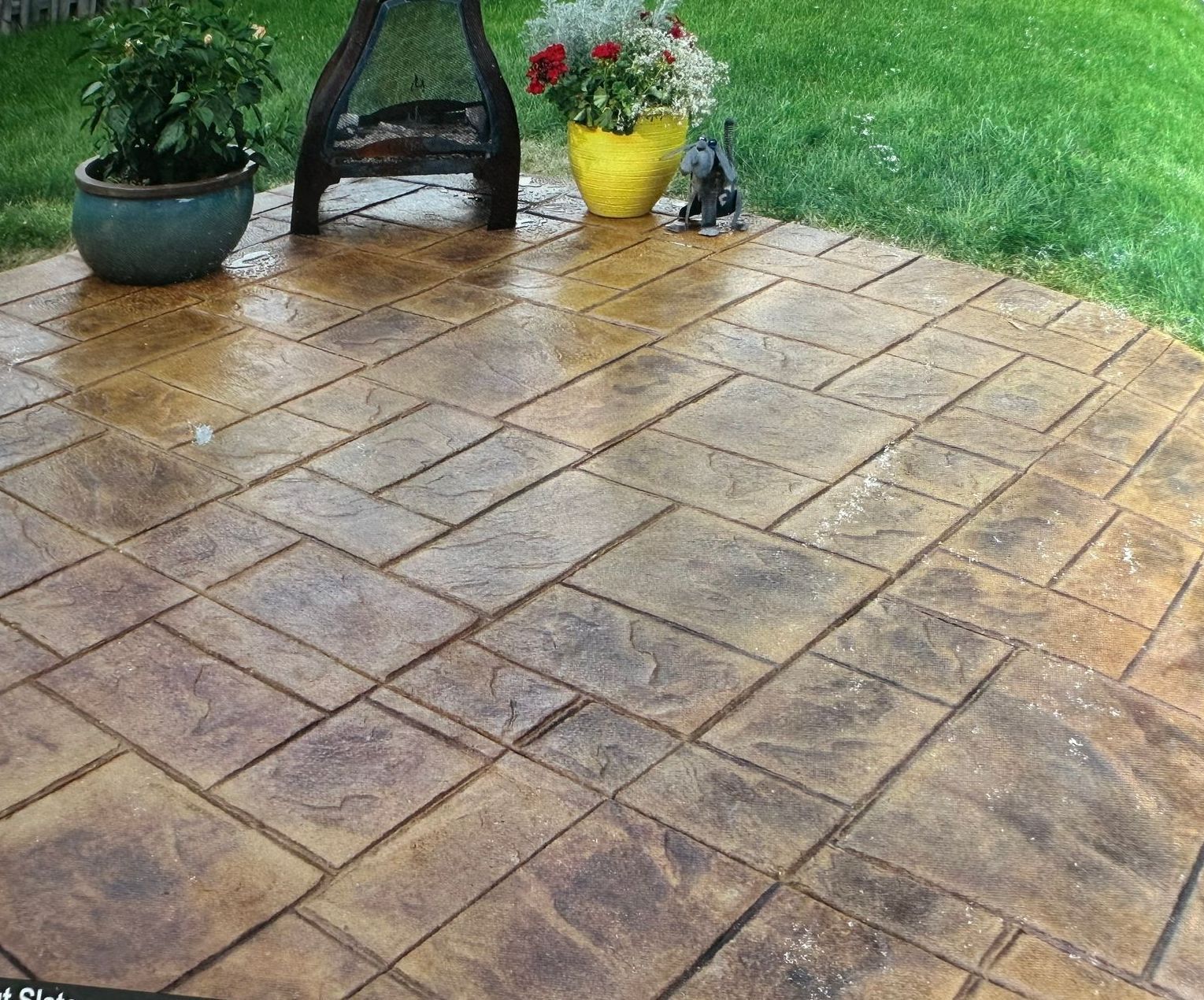 A patio with a fire pit and potted plants on it