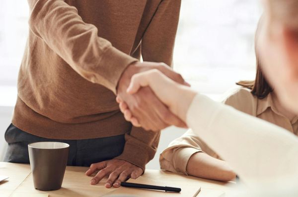 A man and a woman are shaking hands over a table.