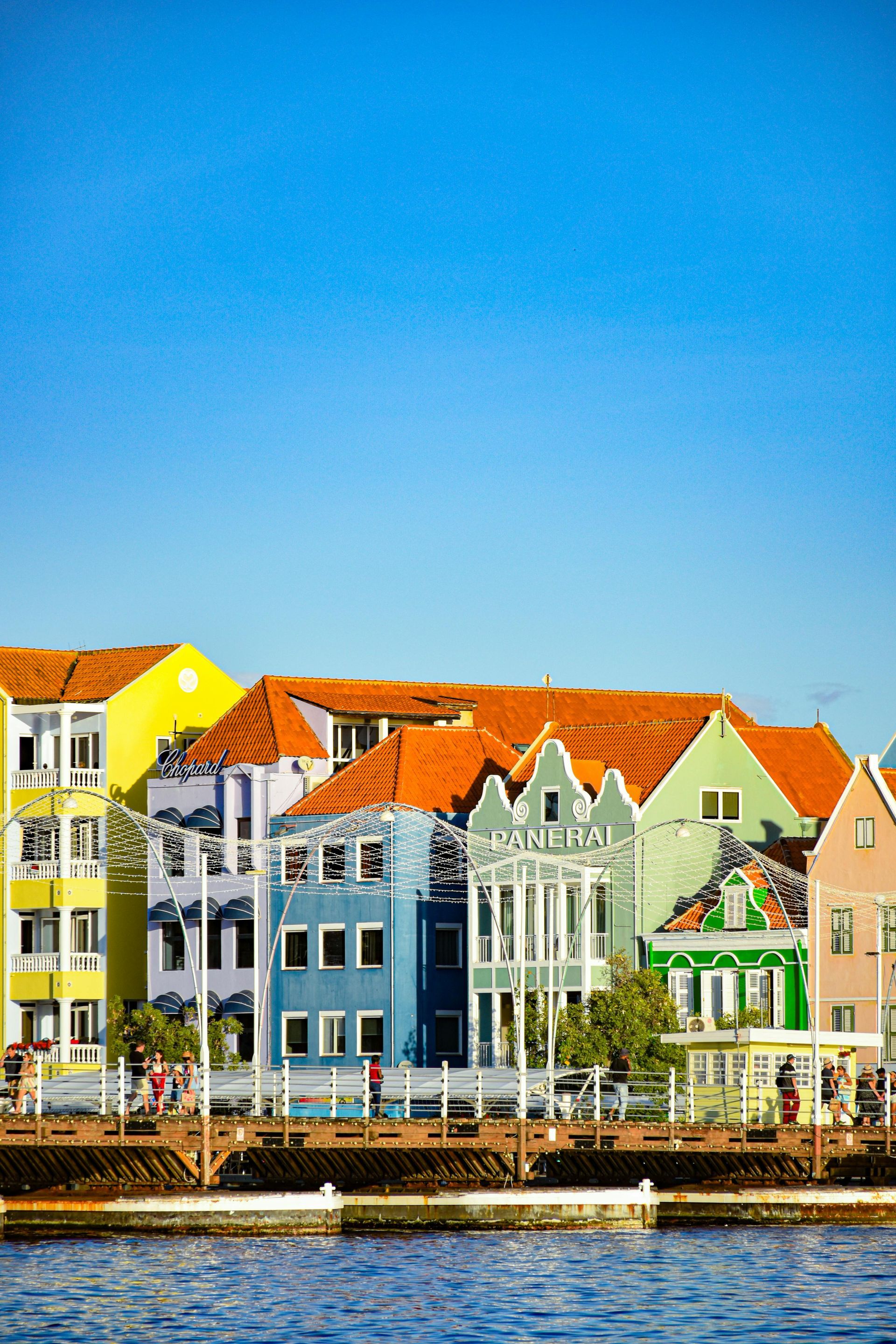 Colorful buildings along a waterfront, under a bright blue sky.