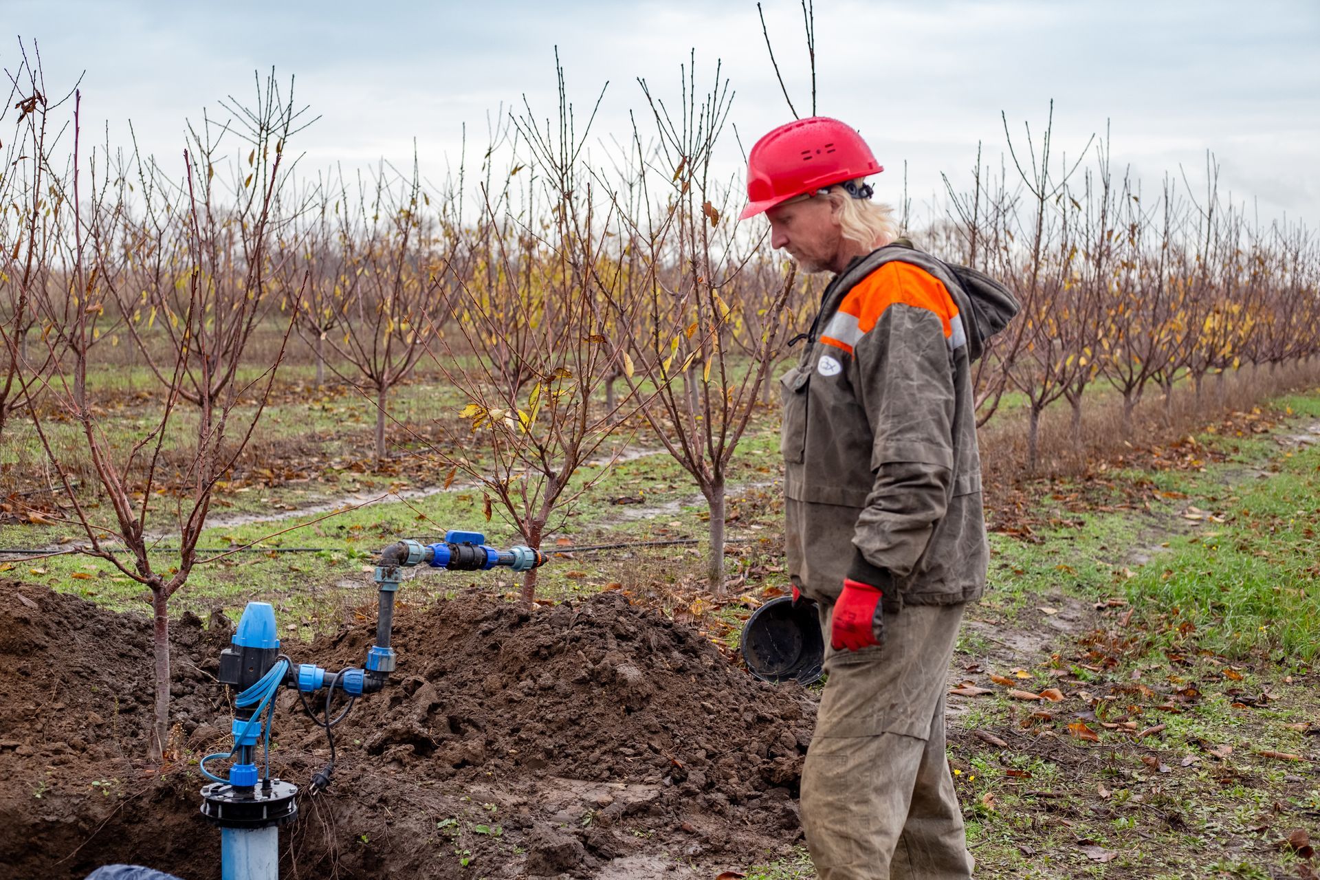 Technician inspecting an exposed well pump valve at an excavation site.