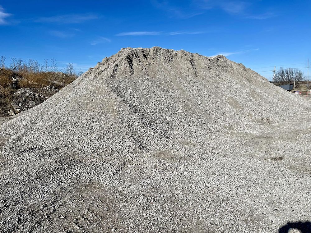 A large pile of gravel is sitting on top of a dirt field.