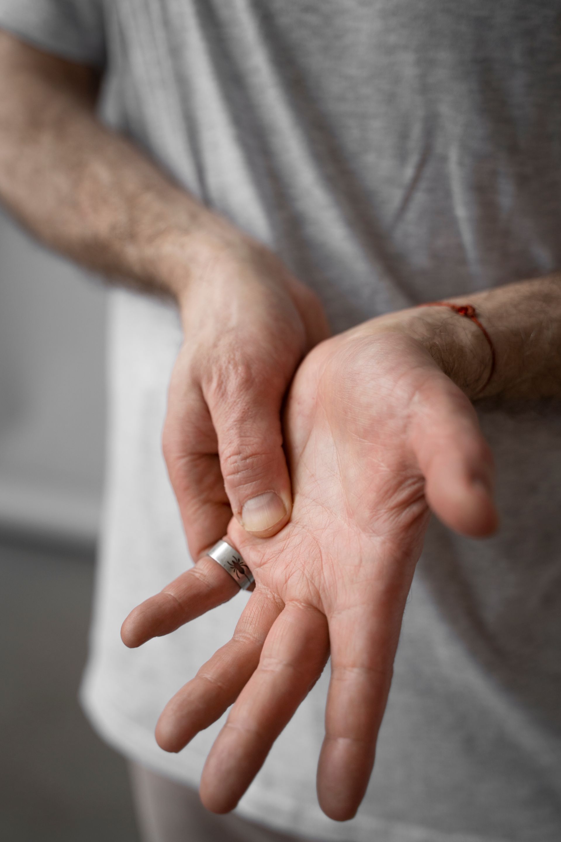 A man wearing a ring on his finger is holding his hands together.