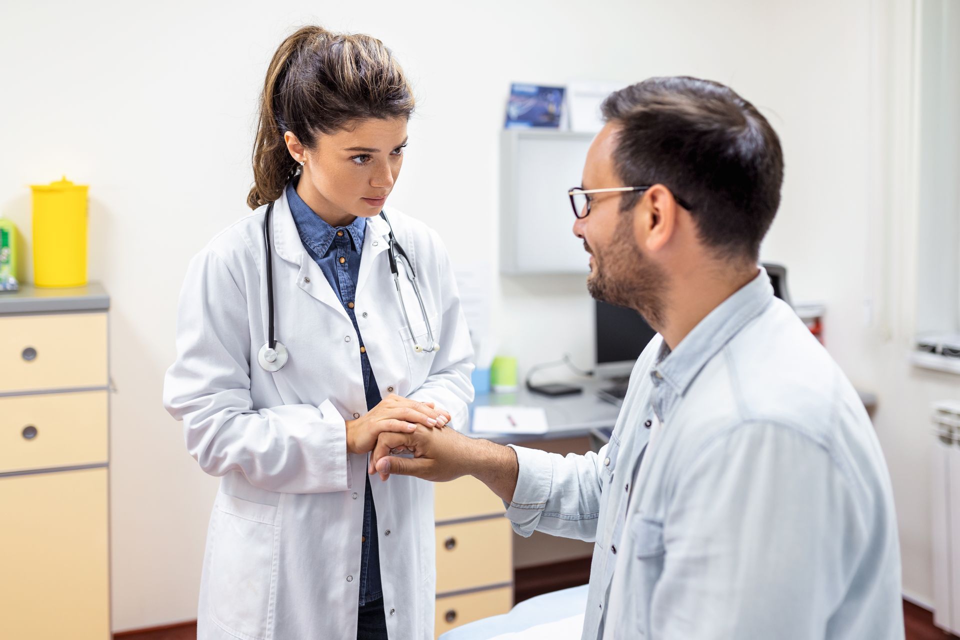 A doctor is holding the hand of a patient in a hospital.