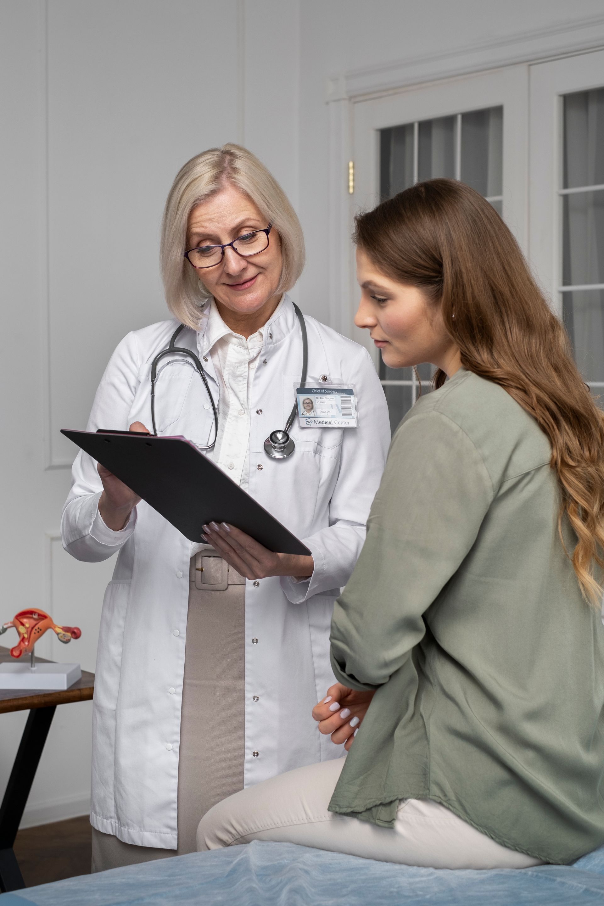 A doctor is talking to a patient who is sitting on a bed.