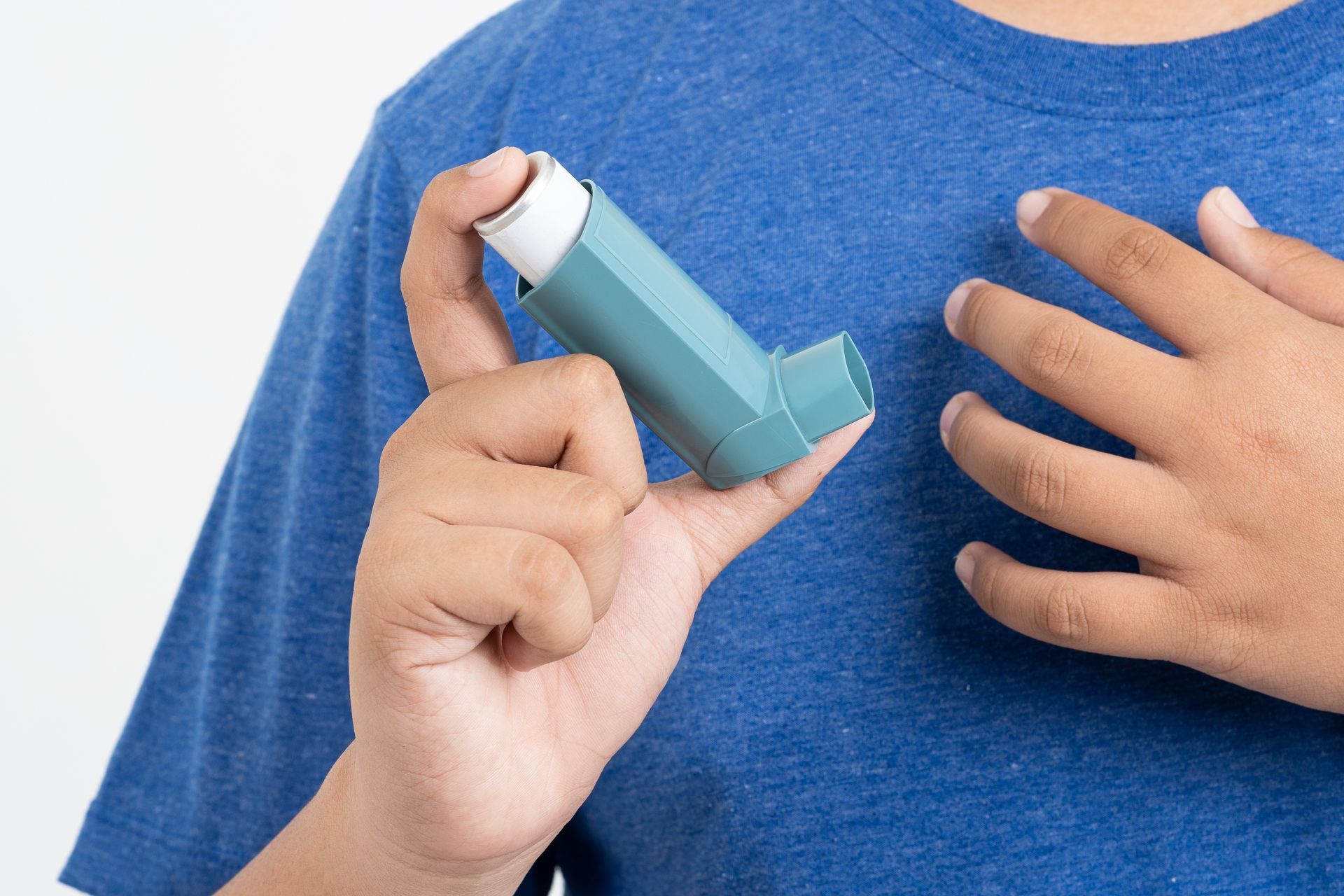 A person is holding an inhaler in front of their chest.