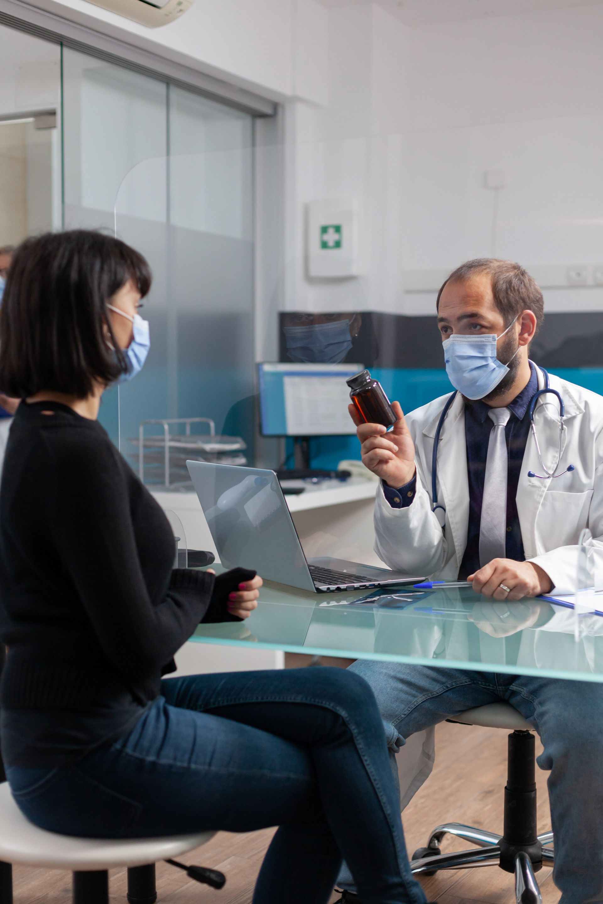 A doctor is talking to a patient who is wearing a mask.