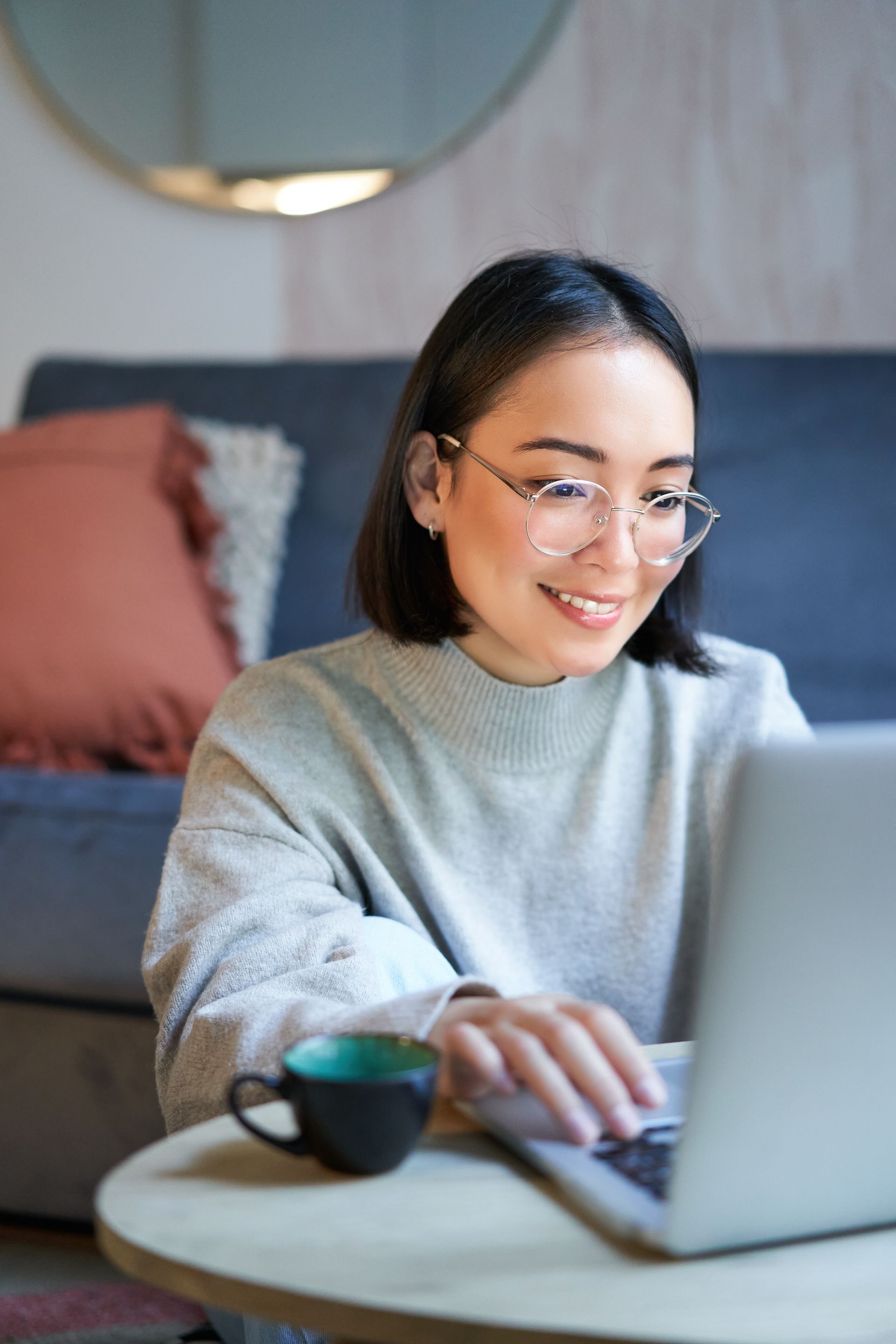 A woman is sitting at a table using a laptop computer.