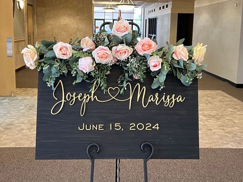 A wooden sign with the names joseph and marissa written on it is sitting on top of a metal stand.