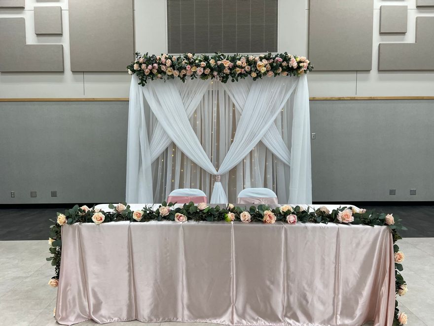 A table with a pink tablecloth and flowers on it in a room.