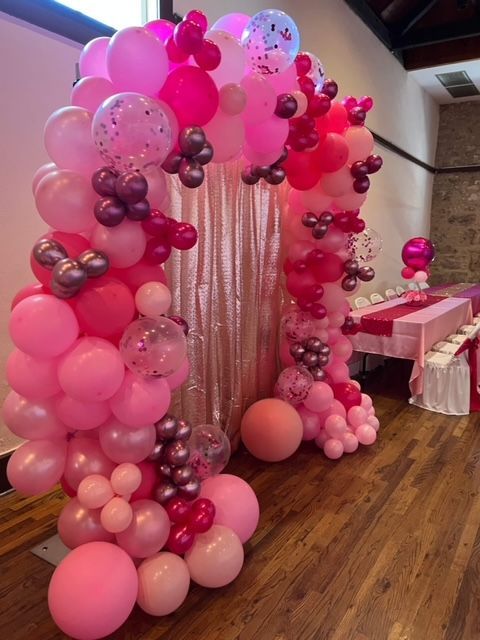 A bunch of pink balloons are sitting on a wooden floor.