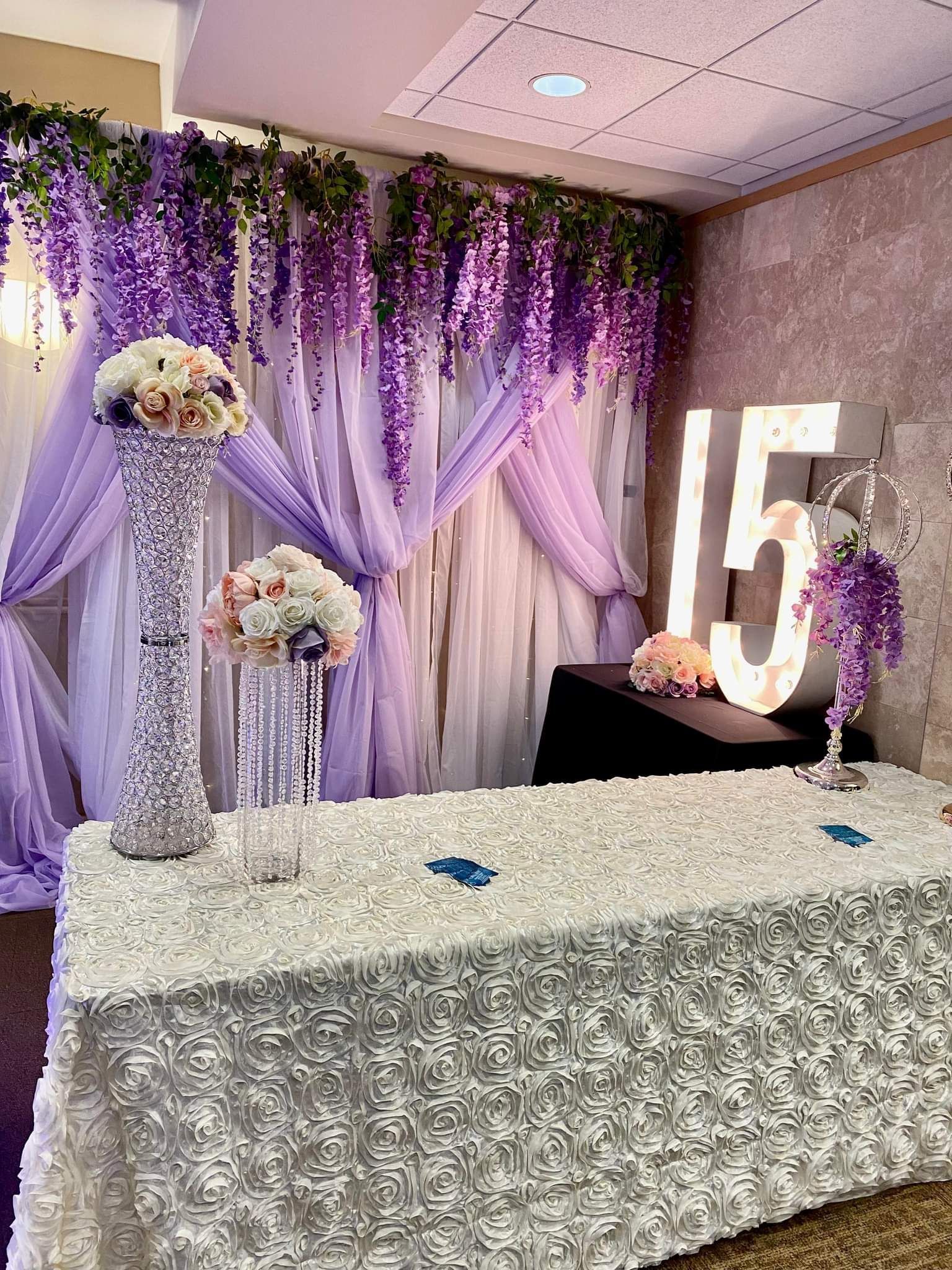 A table with a white tablecloth and purple flowers on it.