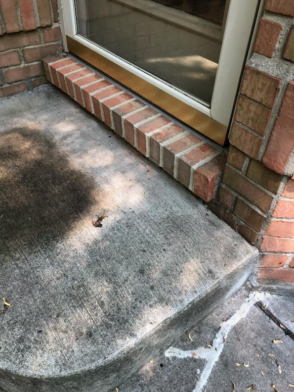 A brick wall with a door and steps next to it.