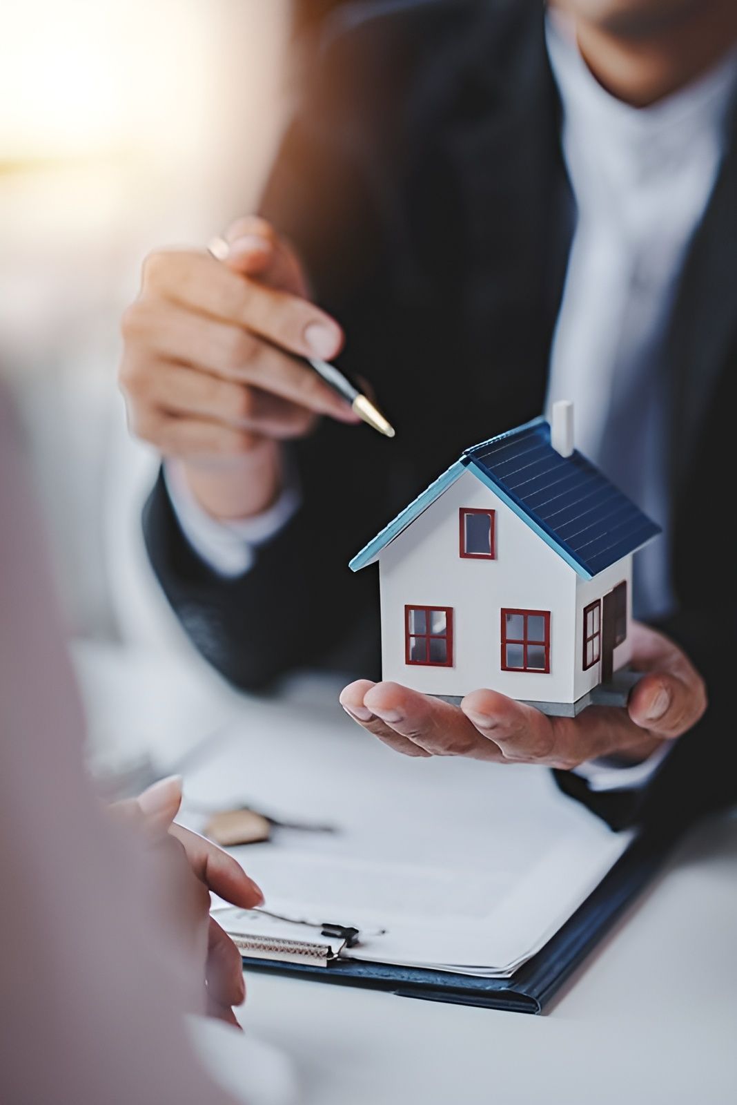 A Man Is Holding A Small Model House In His Hand — Anytime Conveyancing In Nabiac, NSW