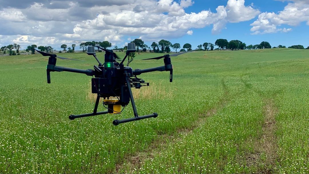 A drone is flying over a grassy field.