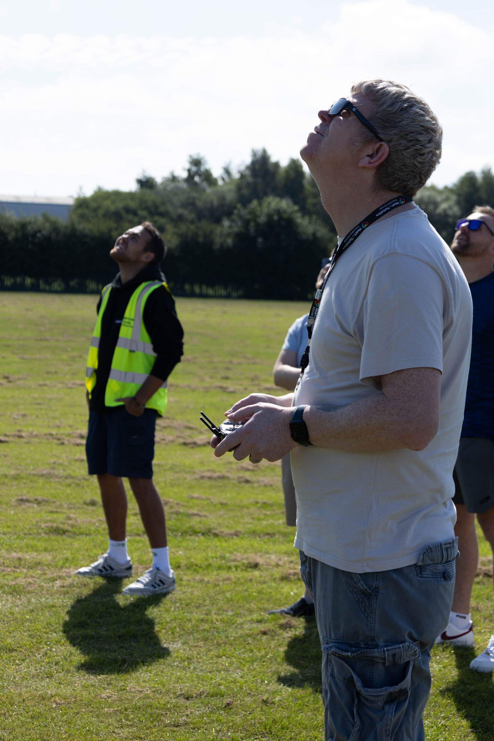 A man is standing in a field holding a remote control.