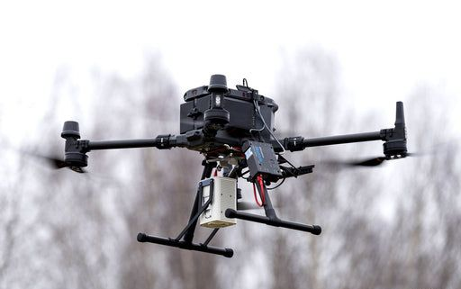 A drone with a camera attached to it is sitting on the ground.