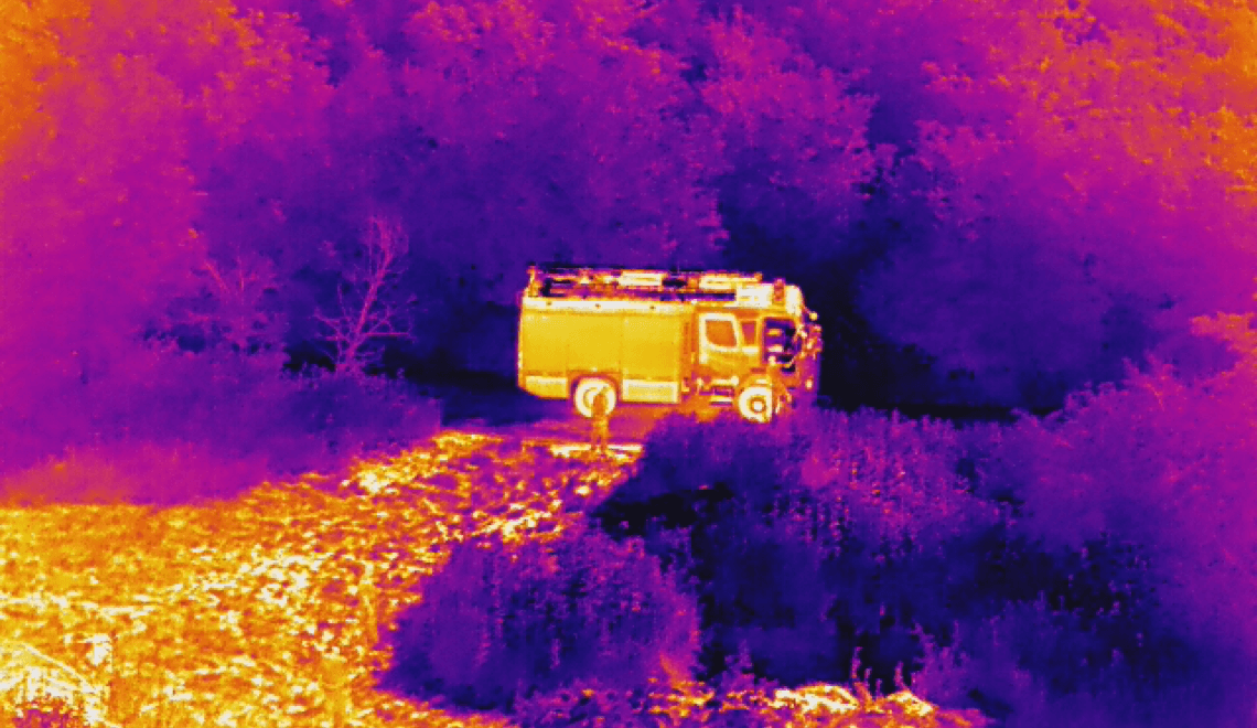 A thermal image of a school bus in the woods.
