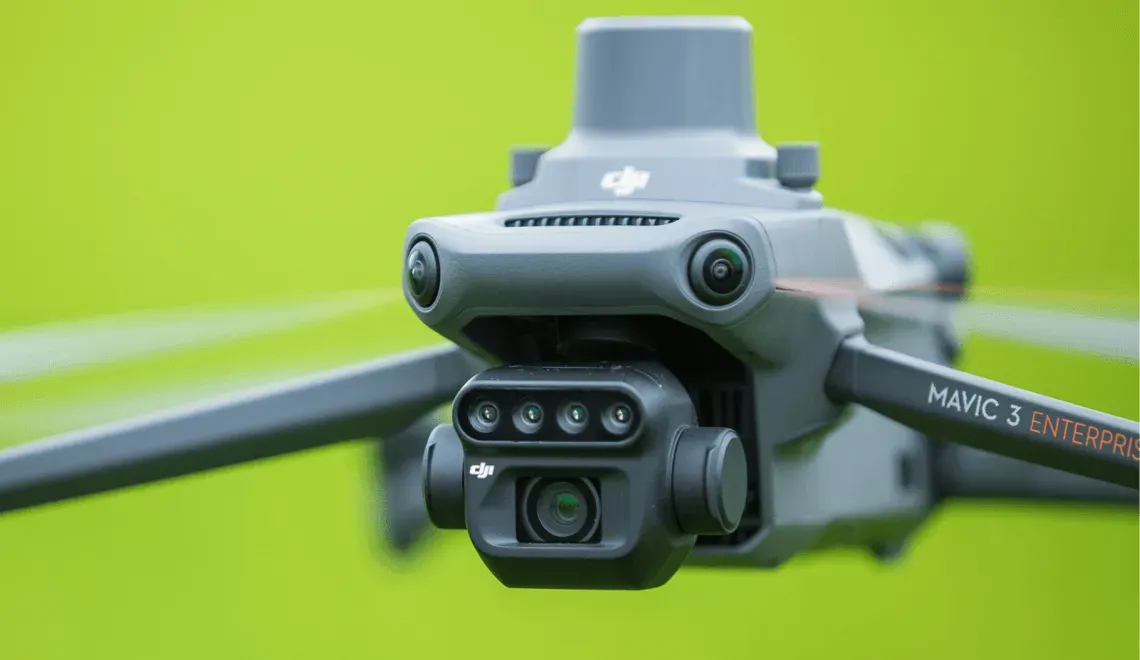 A drone is flying in the air with a green background.