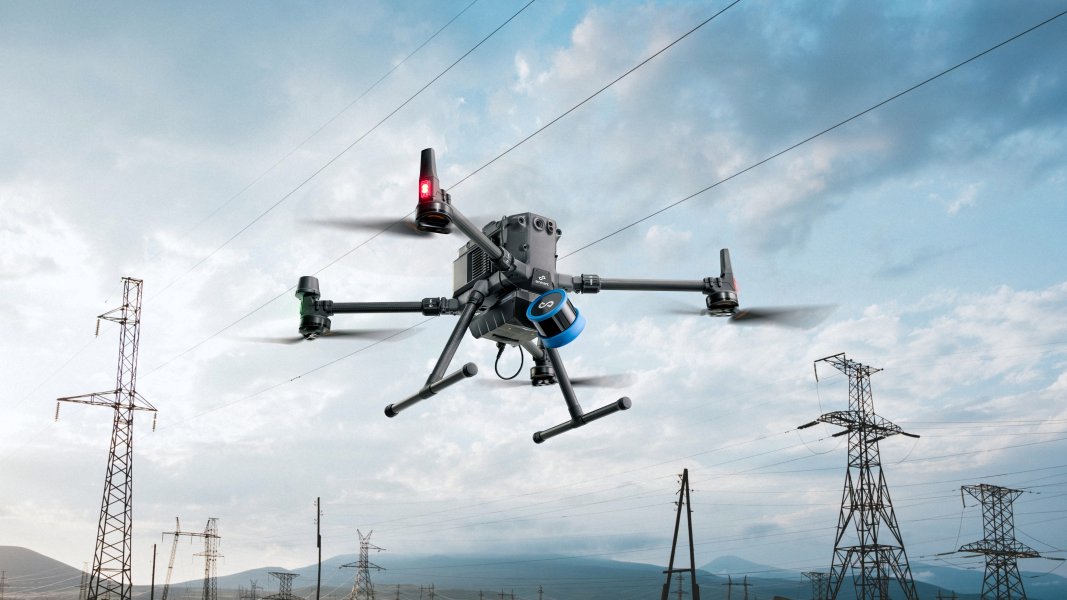 A drone is flying over power lines in a field.