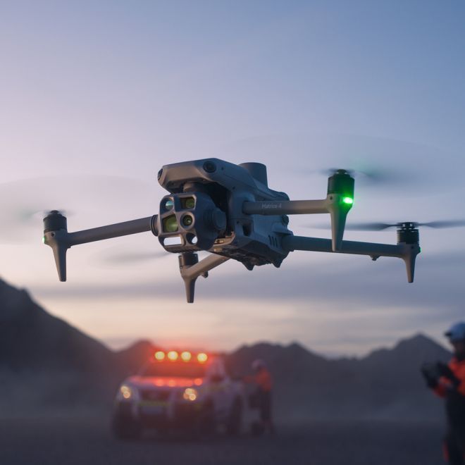 A drone is flying in the air with trees in the background.