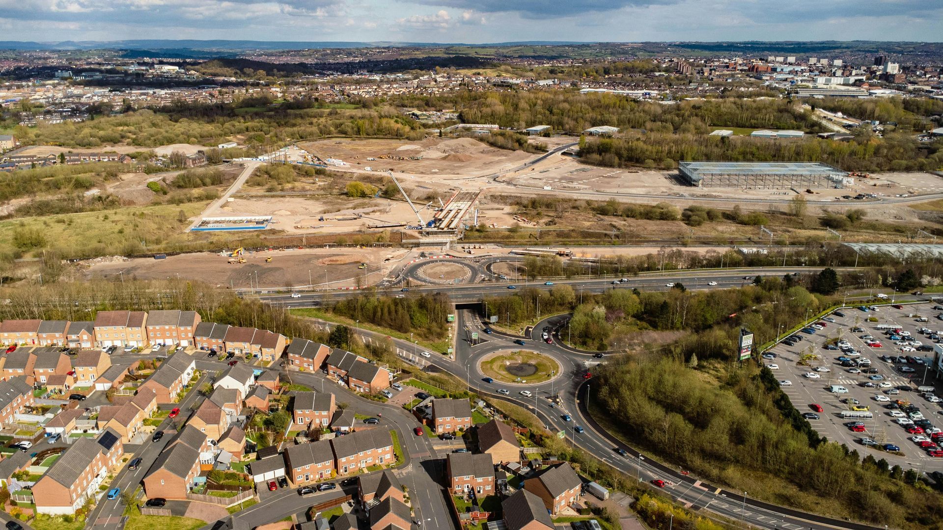 An aerial view of a residential area with a roundabout and a parking lot.