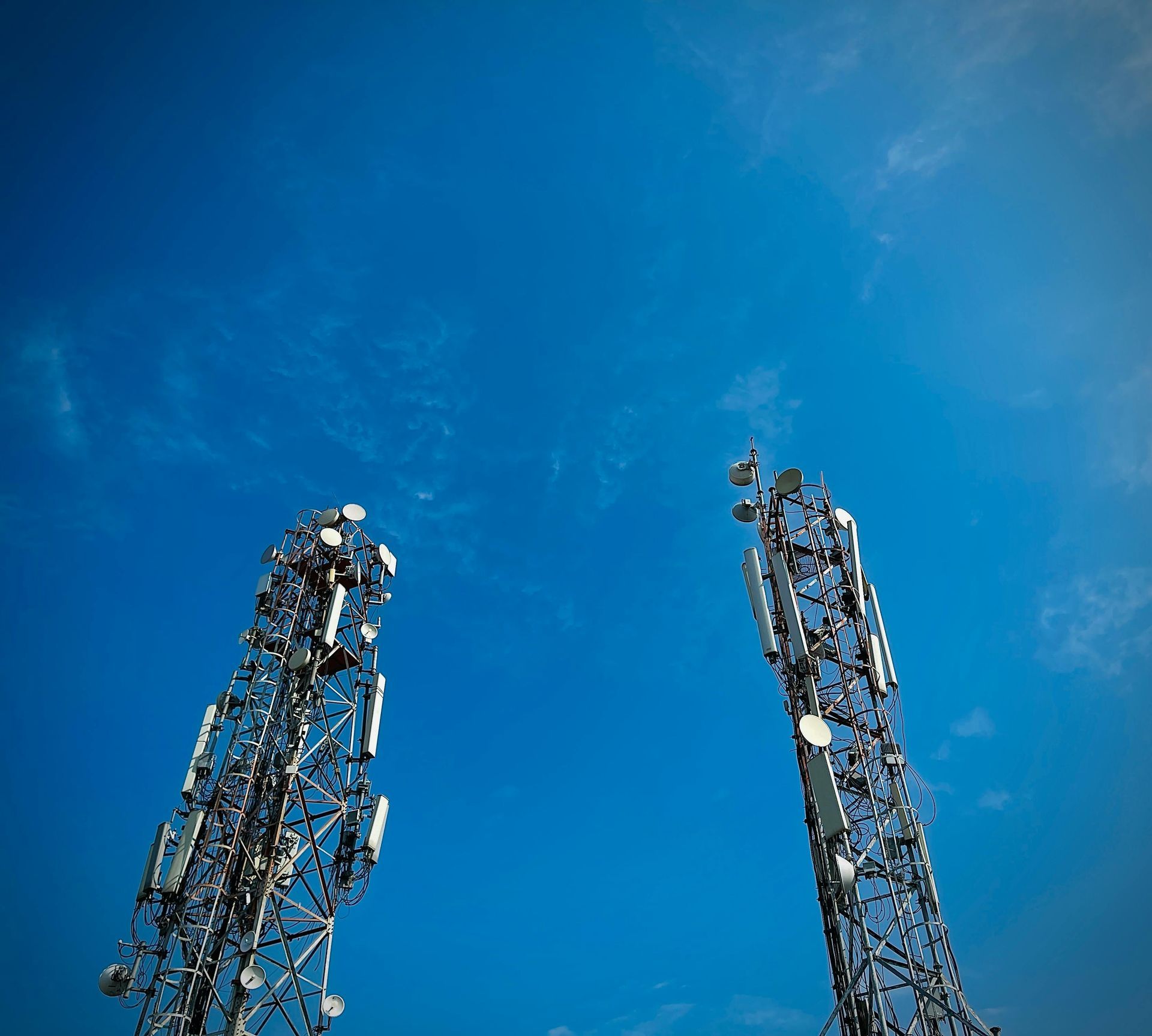 Two telephone towers against a blue sky with clouds