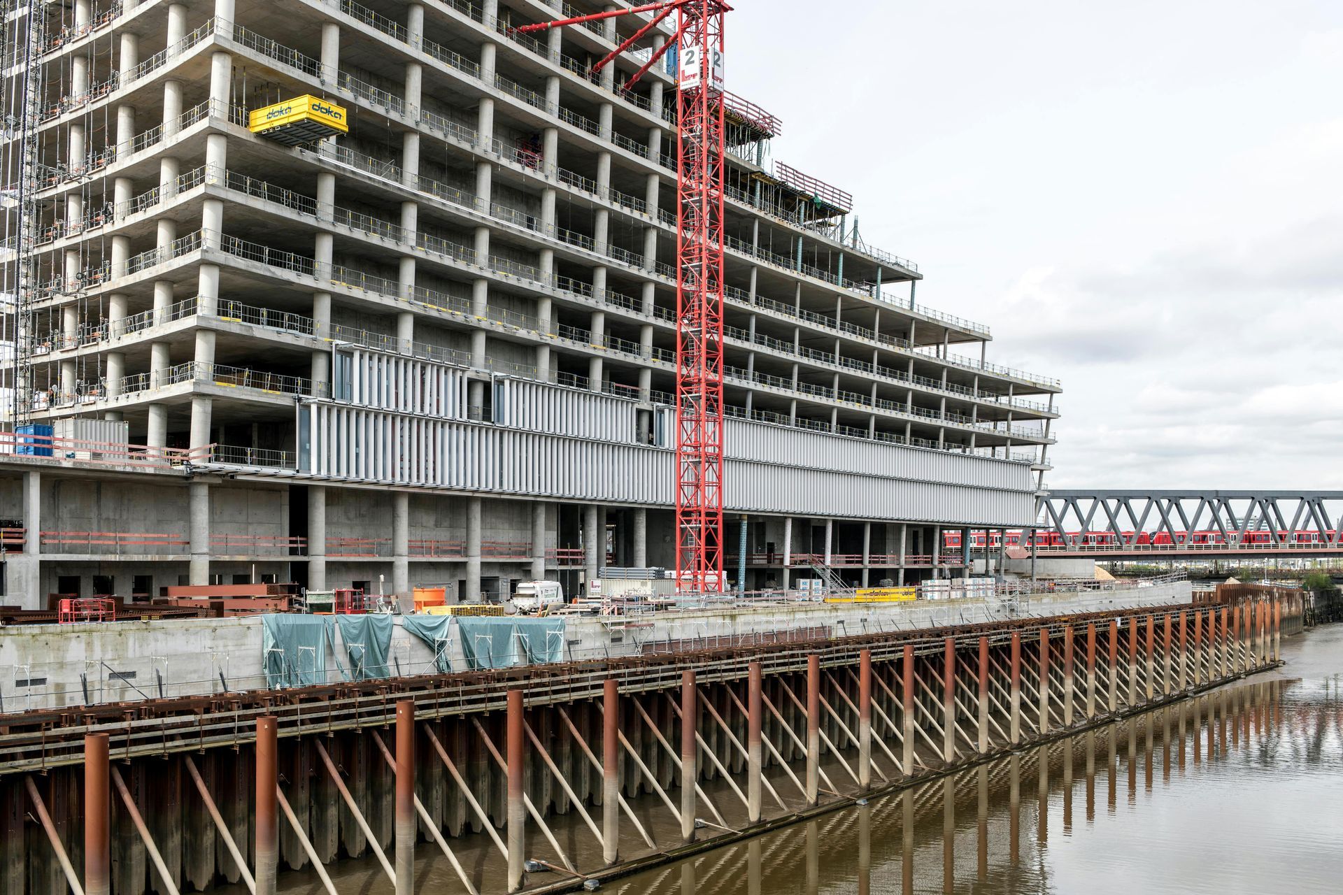 A large building is being built next to a body of water.