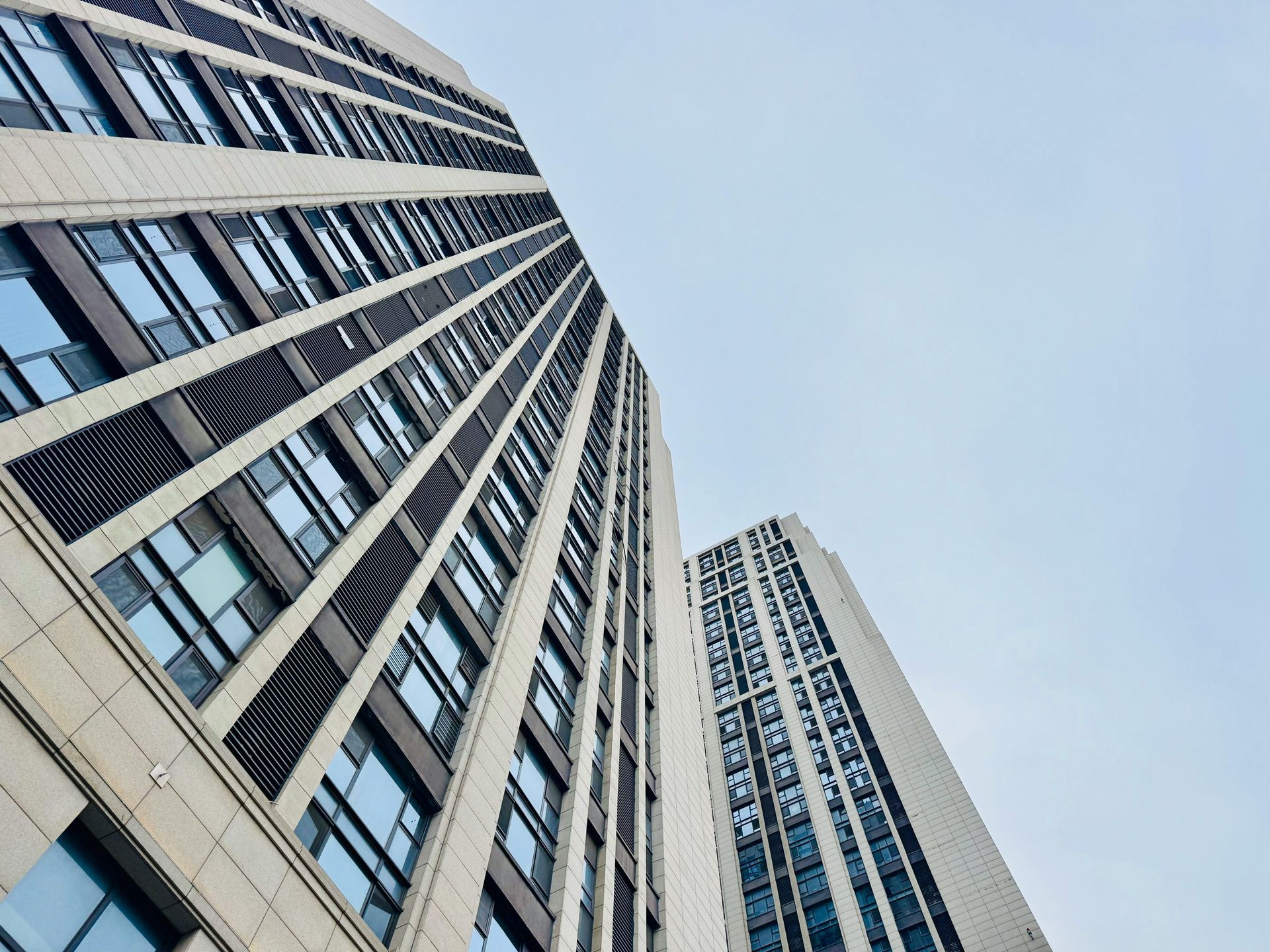 Looking up at a tall building with lots of windows against a blue sky.