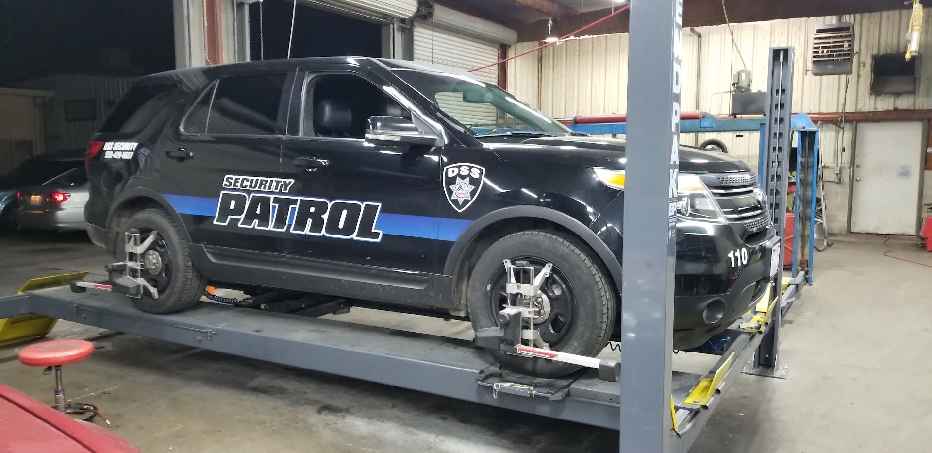 Black police SUV on a lift in a garage, undergoing alignment | My Automotive