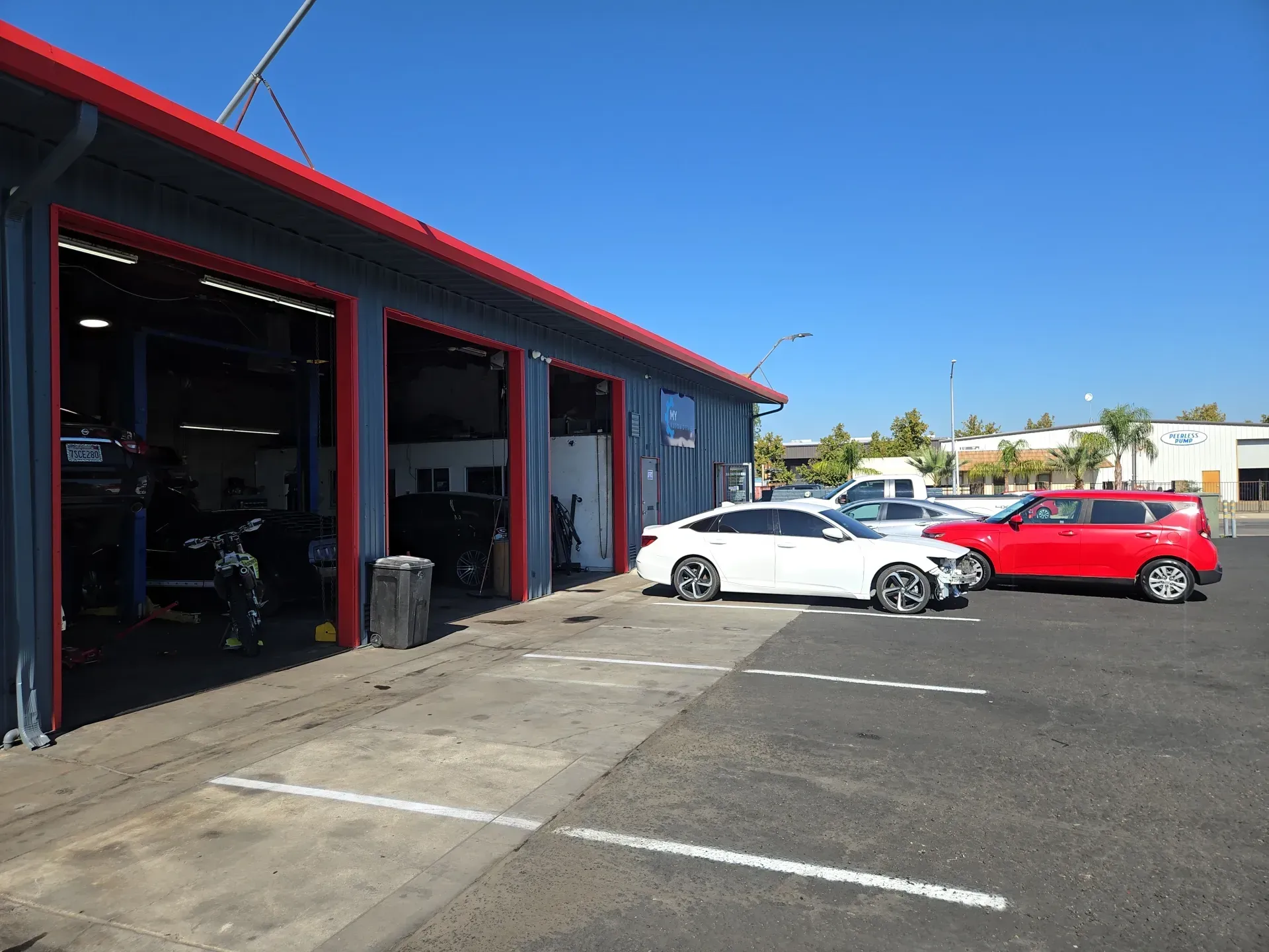 New asphalt paving in front of warehouse; orange traffic cones and caution tape mark boundaries | My Automotive