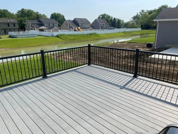 A gray deck with a black railing overlooking a body of water