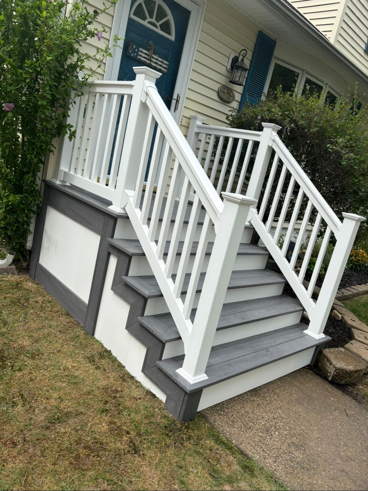 A white house with a porch and stairs in front of it.