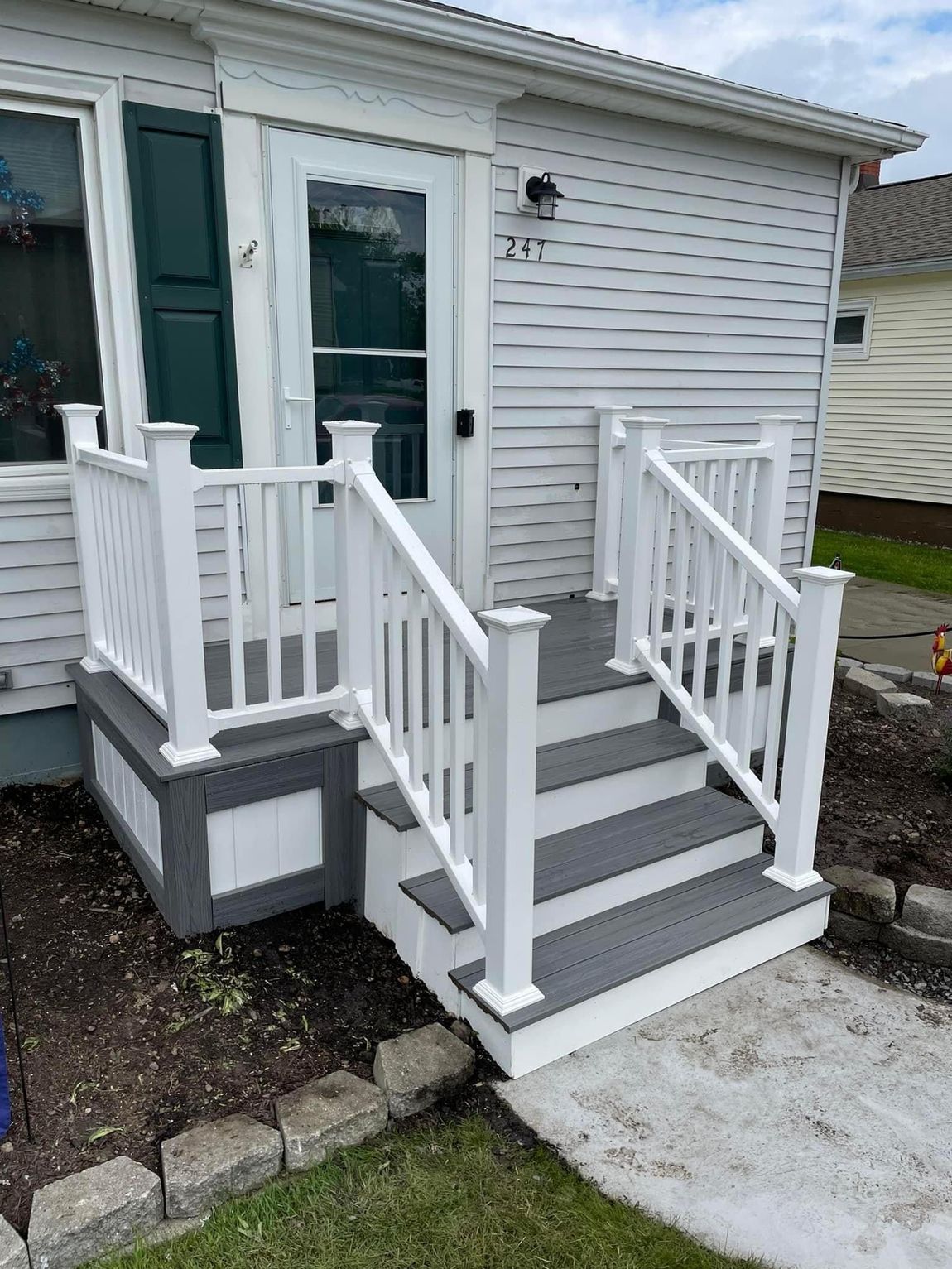 A white house with a porch and stairs in front of it.