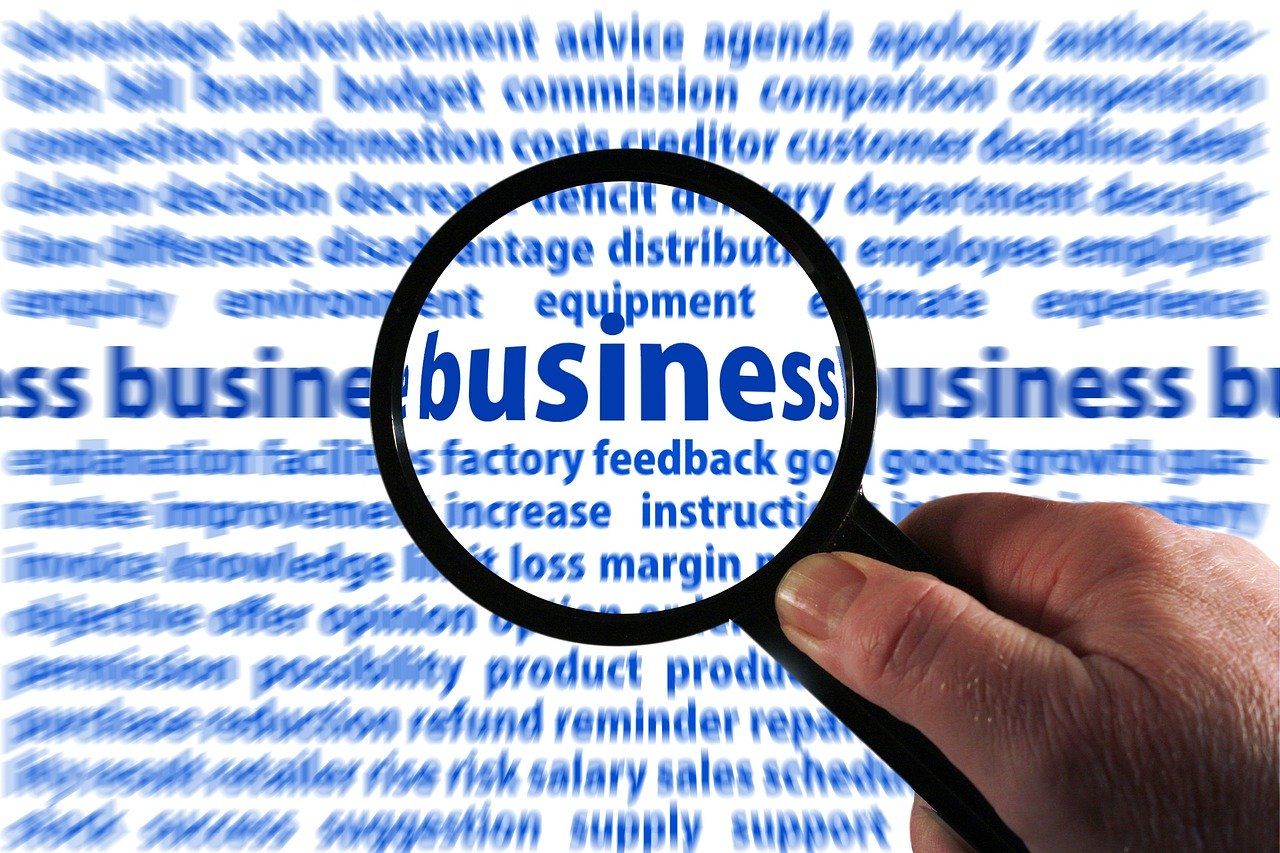 A person is holding a magnifying glass over the word business