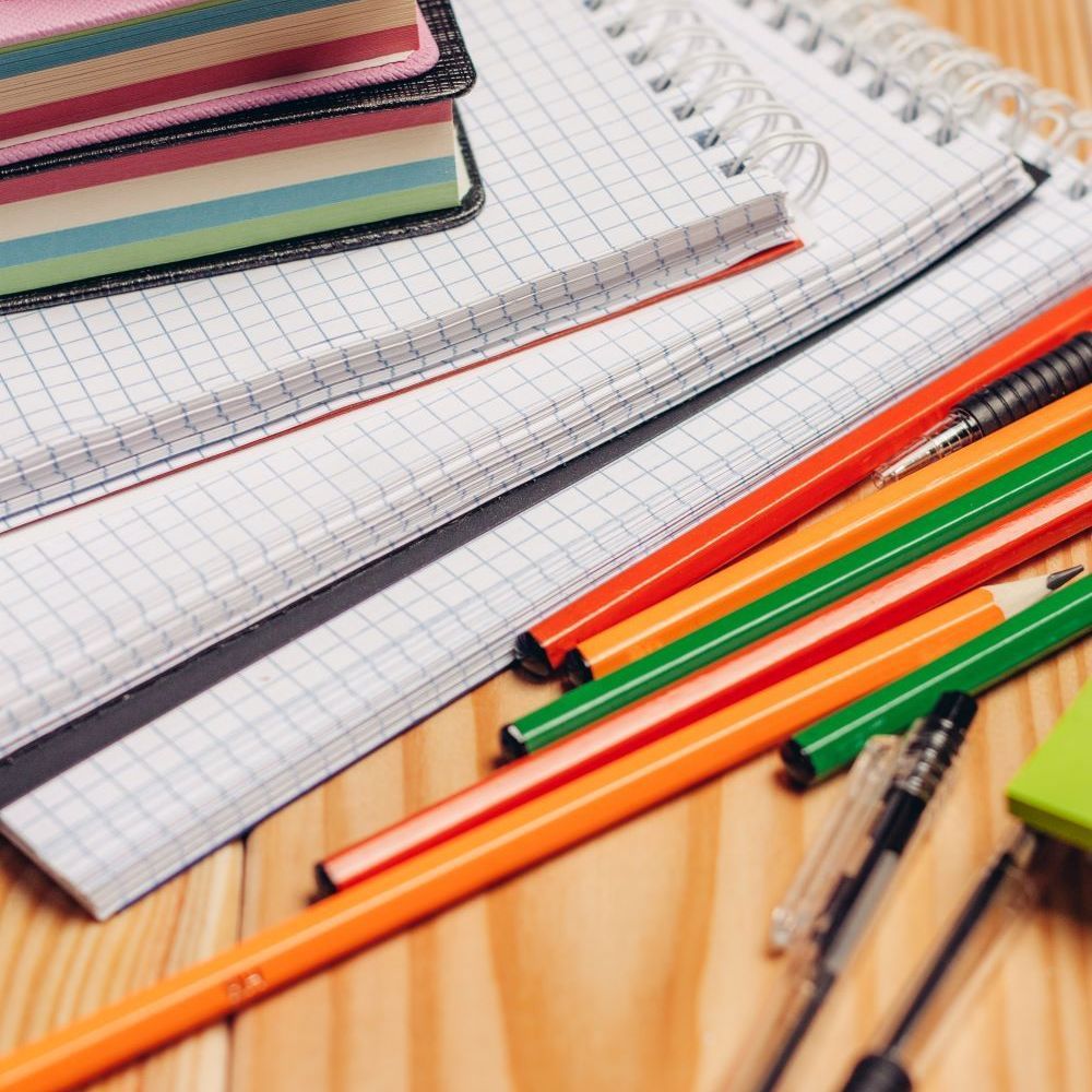 A stack of notebooks and pencils on a wooden table