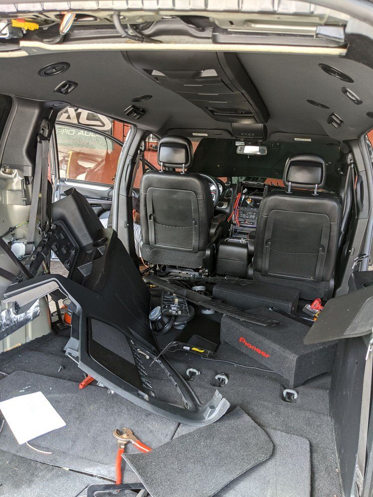 Interior of a van with seats, dashboard, and panels removed; tools and debris are scattered about.