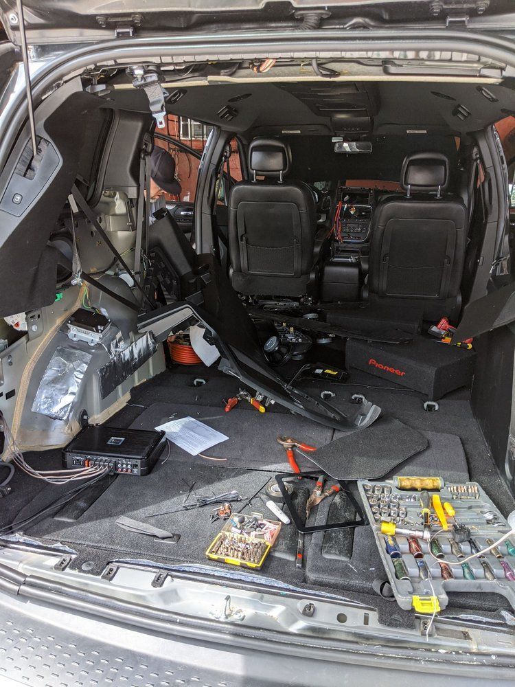 Car's interior gutted, tools scattered. Audio system installation in progress.
