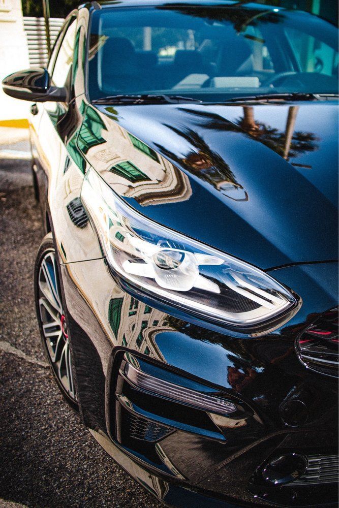 Black car with reflective paint, headlights, and front grill.