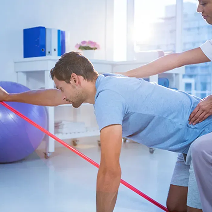 A man is doing push ups with a resistance band while a woman helps him.