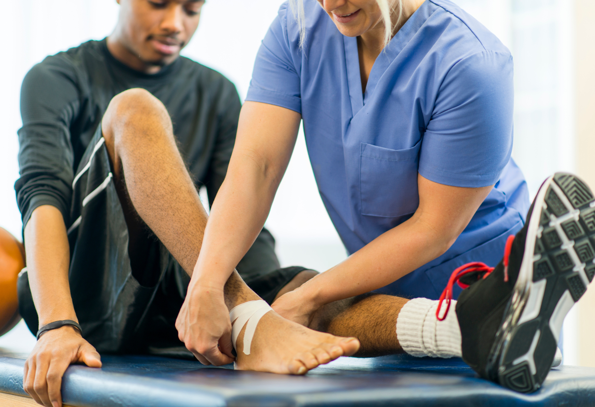 A nurse is helping a man with his ankle wrapped in a bandage.