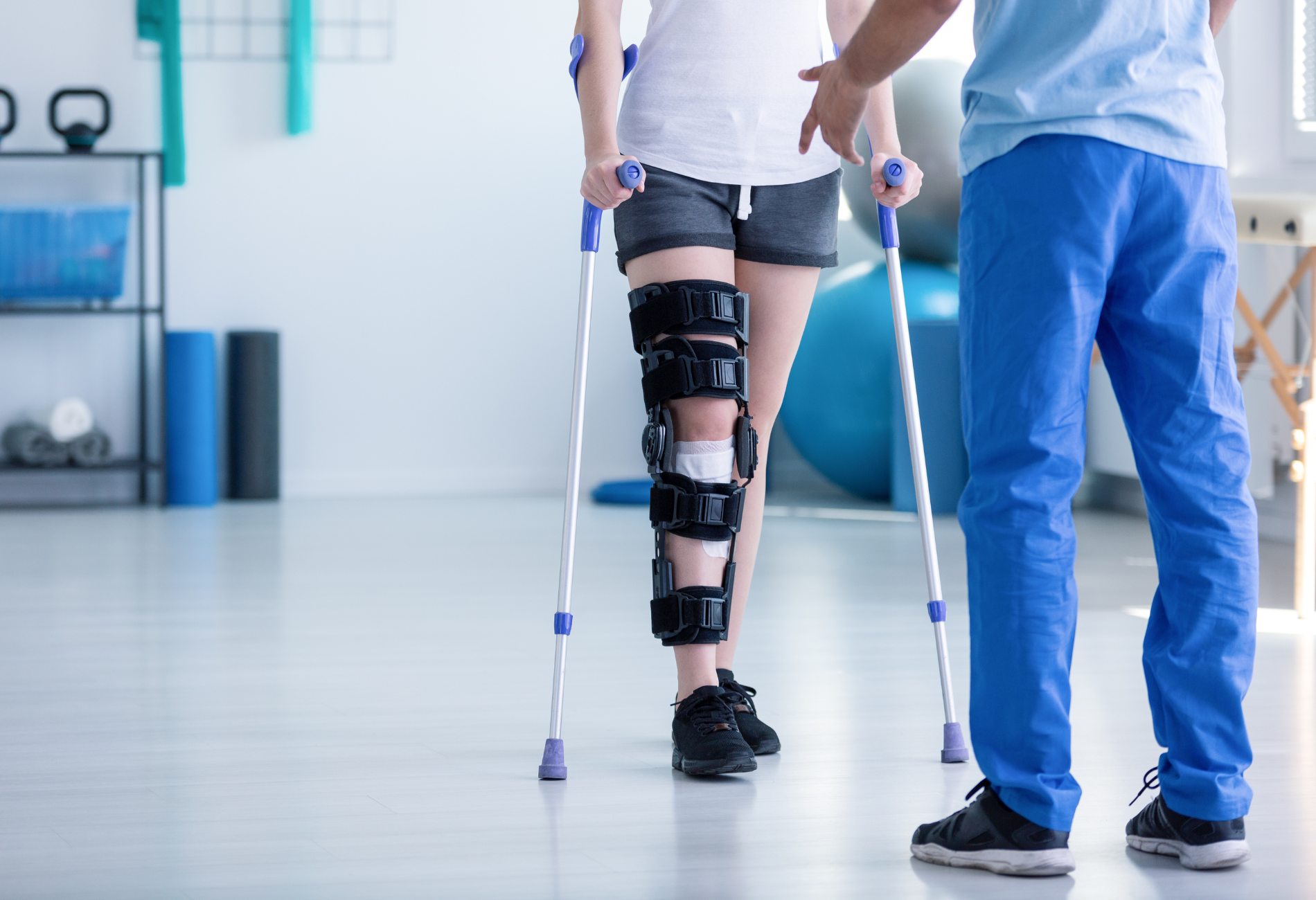 A woman with a knee brace and crutches is being helped by a doctor.