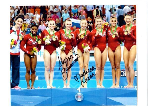A group of female gymnasts are posing for a picture with their medals