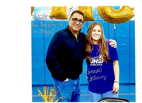 A man and a girl are posing for a picture in front of a blue wall.