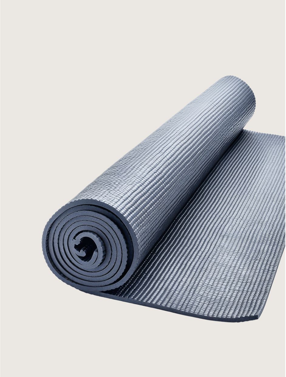 A gray yoga mat is rolled up on a white background.