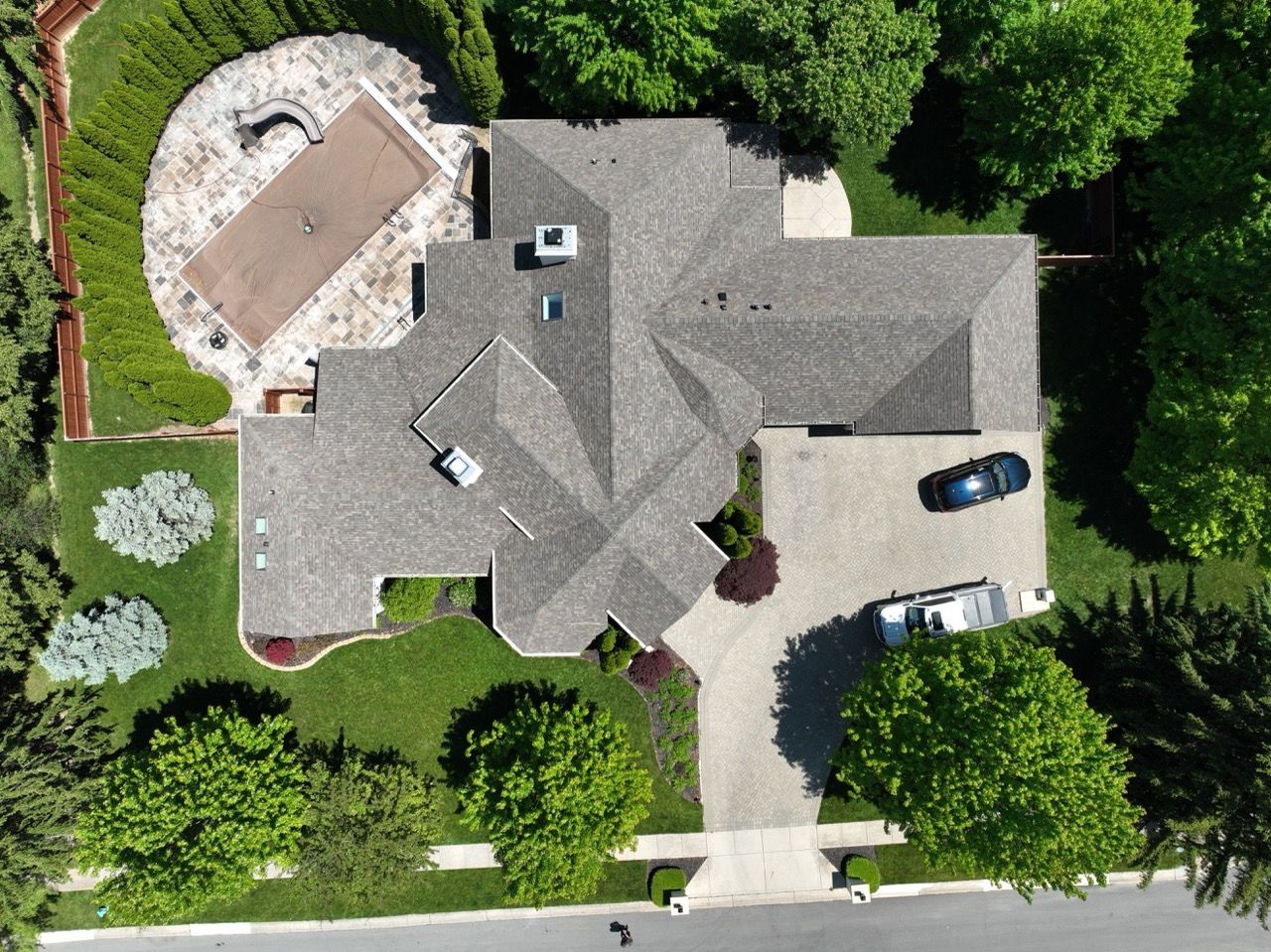 An aerial view of a house with a pool and a car parked in front of it
