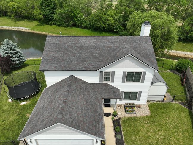 An aerial view of a large white house with a gray roof.