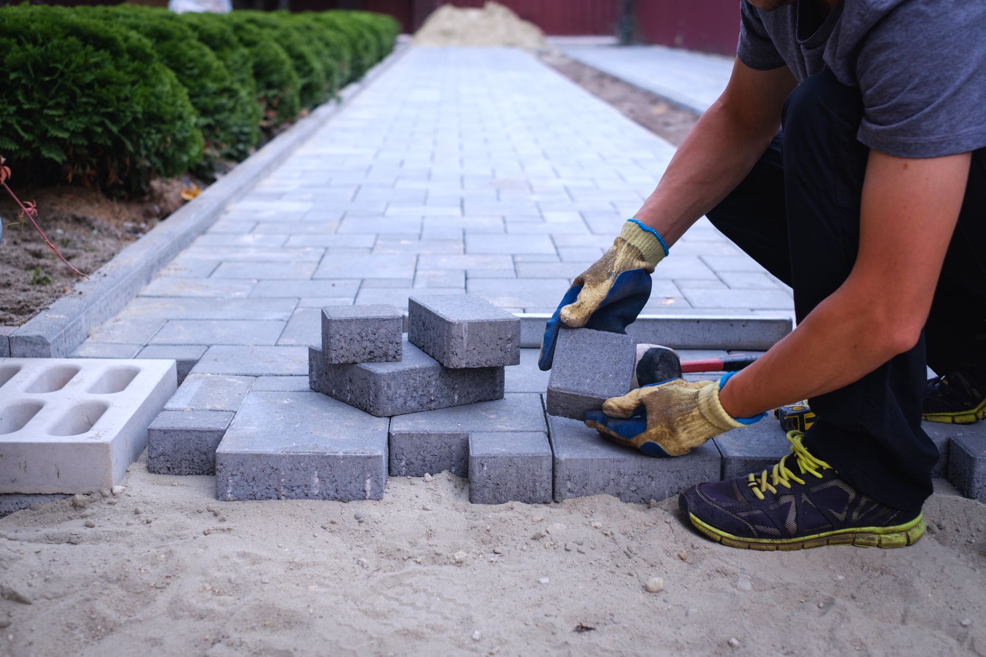 A man is laying bricks on a sidewalk.