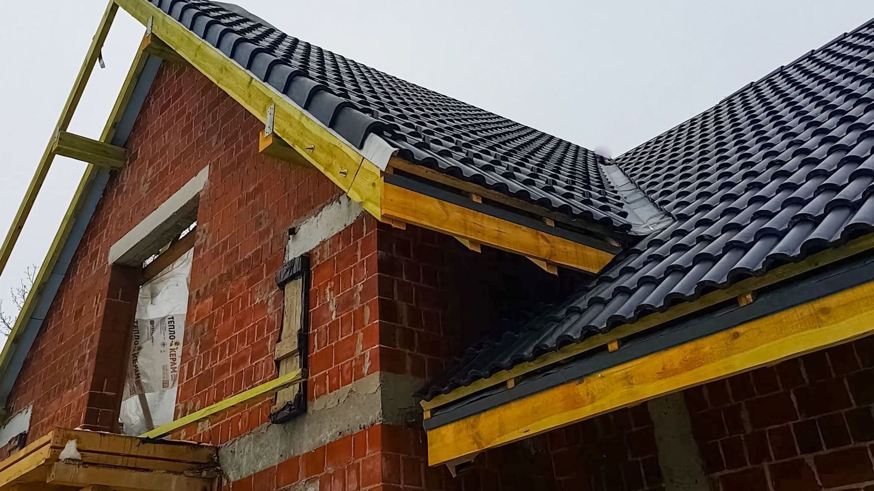 A brick building under construction with a tiled roof.